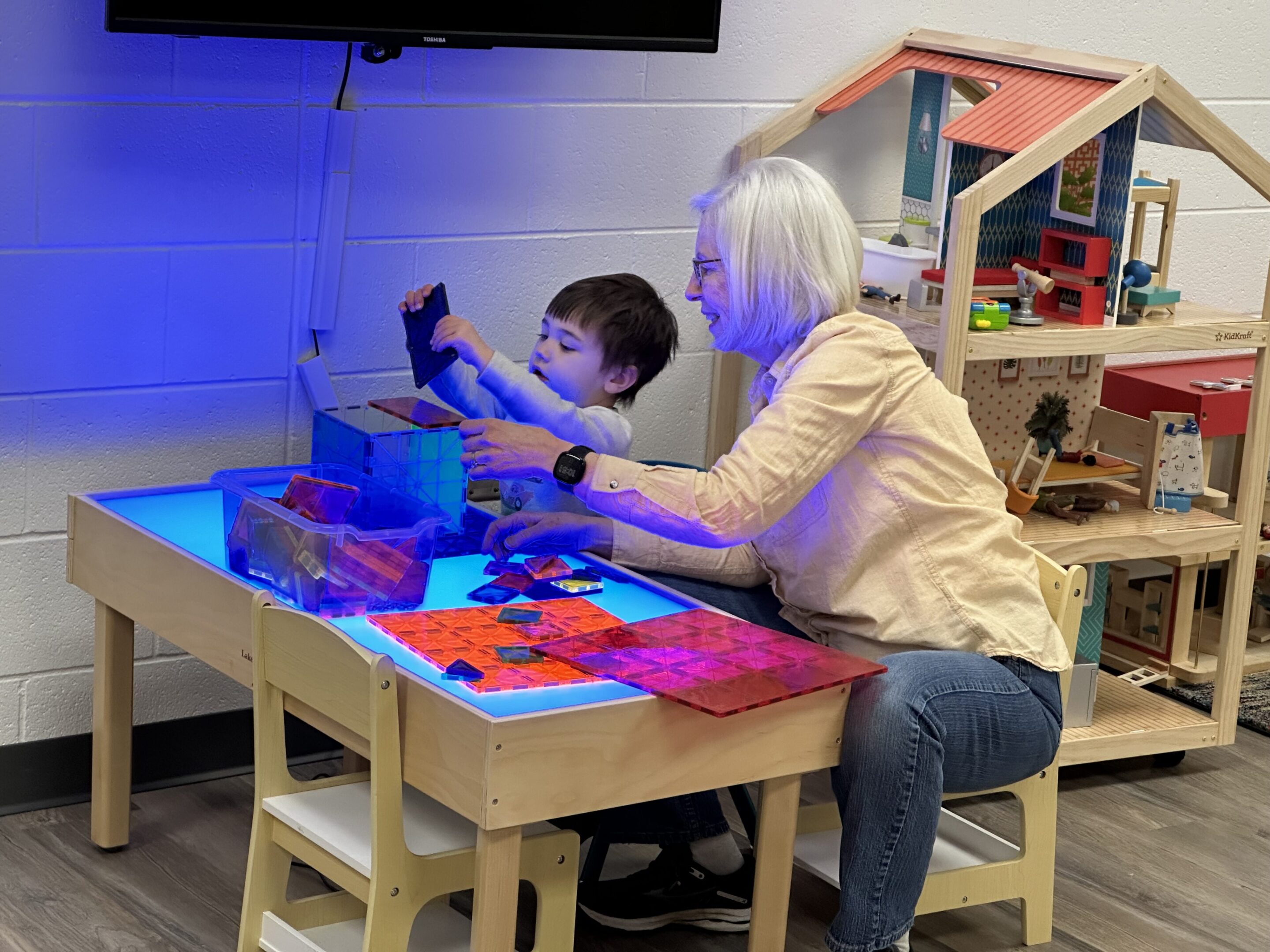 A child and adult crafting together at a table with colorful materials.