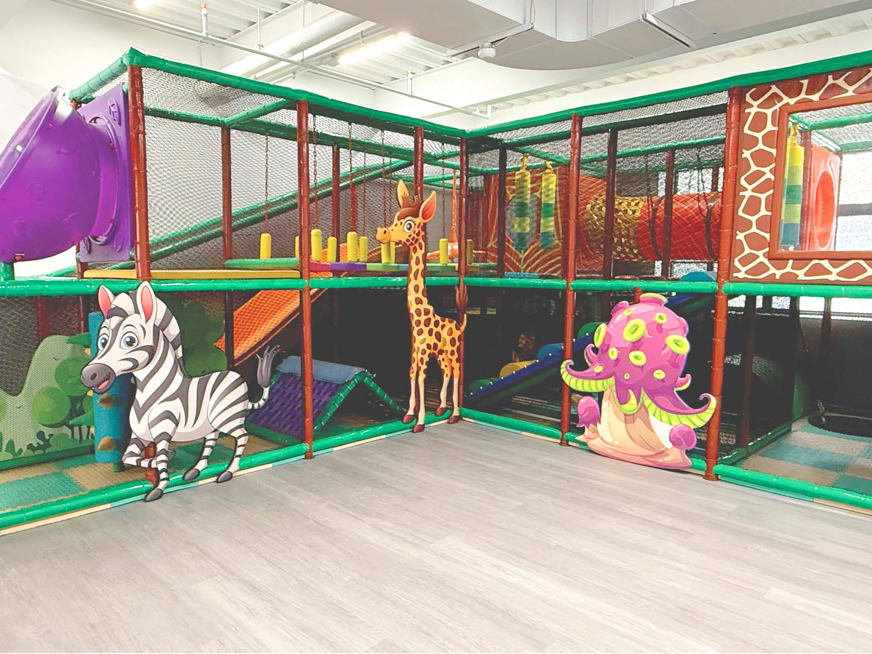 Colorful indoor playground with animal-themed play structures and netted climbing areas.