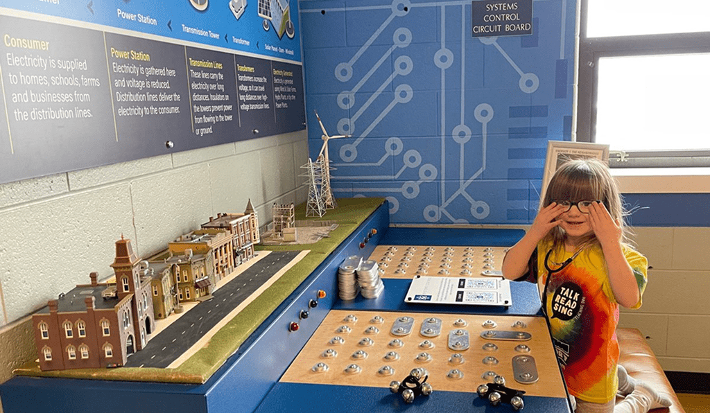 A person playing a complex board game with detailed miniatures on a tech-themed table.