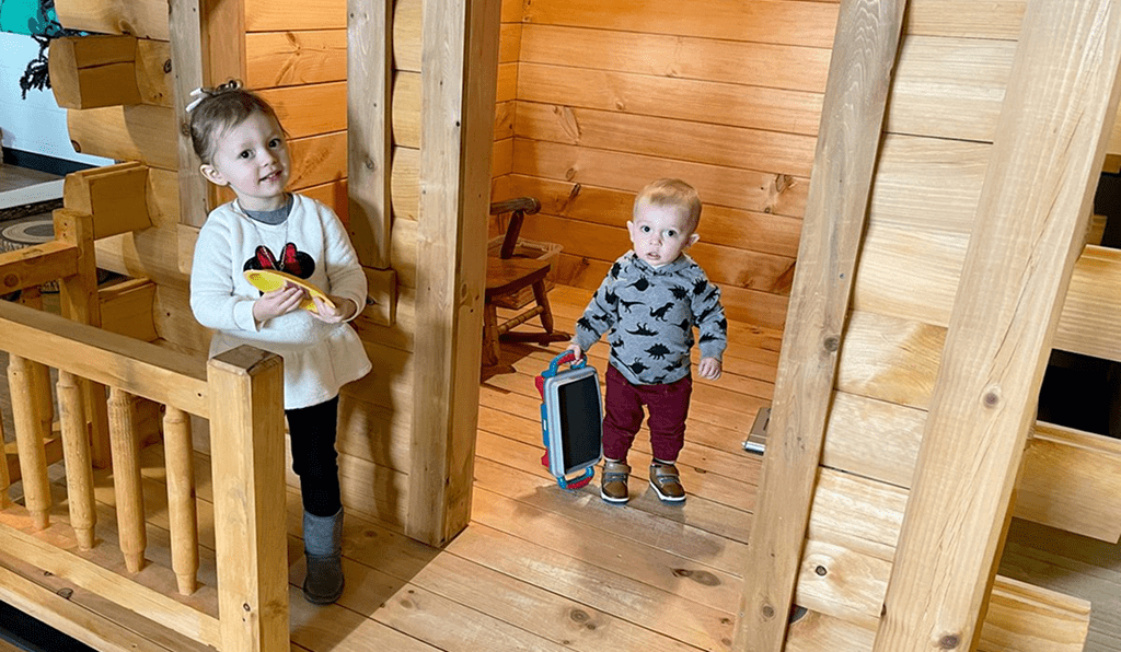 Two young children playing indoors in a wooden room.