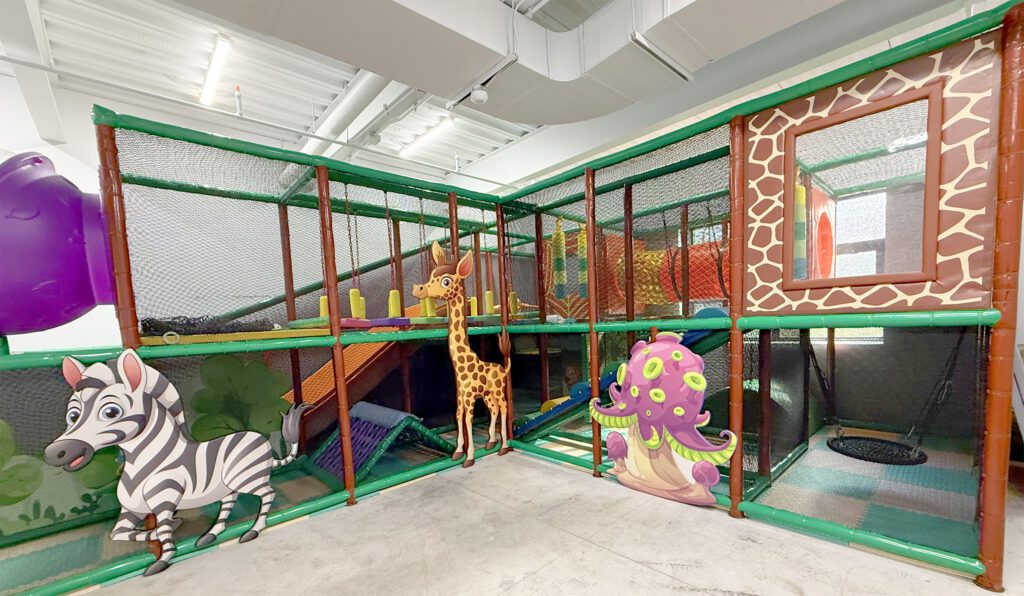 Indoor playground with giraffe-themed play structures and colorful decorations.